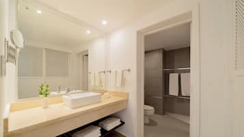 Un baño moderno con un espejo grande, un lavamanos, un inodoro y una zona de ducha.