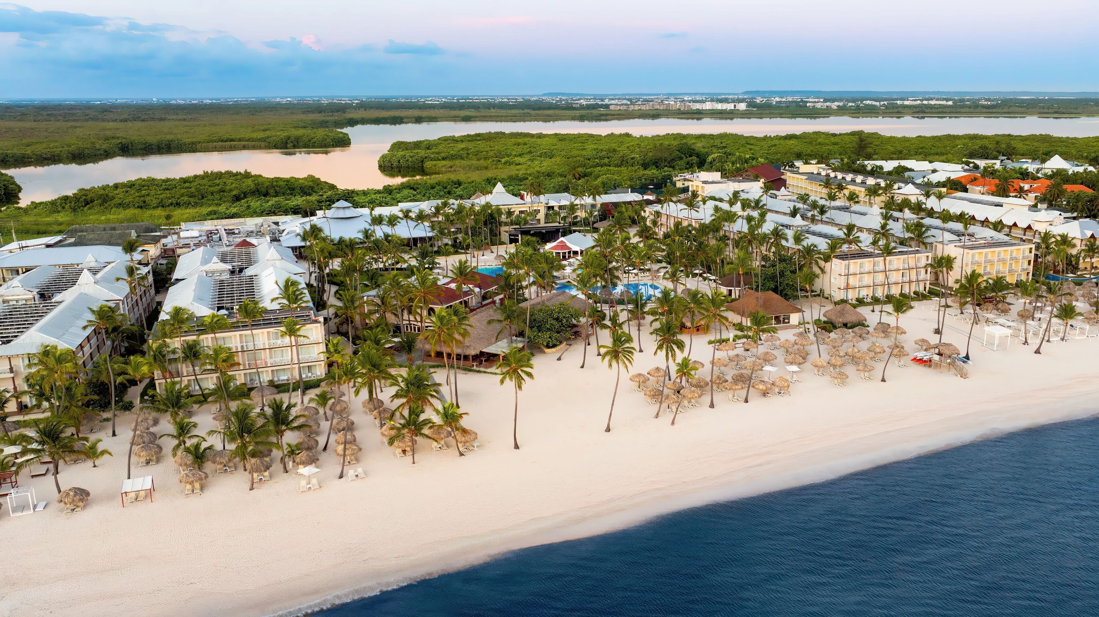 An aerial view of a resort with multiple buildings, a beach, and a lagoon.