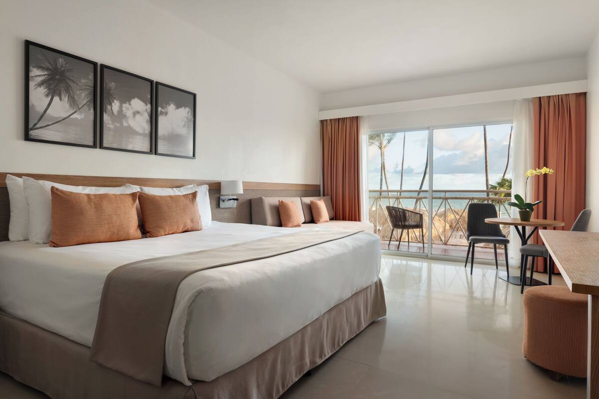 Una habitación de hotel con una cama grande, un escritorio y vistas al océano.