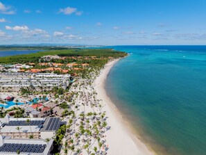 A resort with a beach, palm trees, and a view of the ocean.