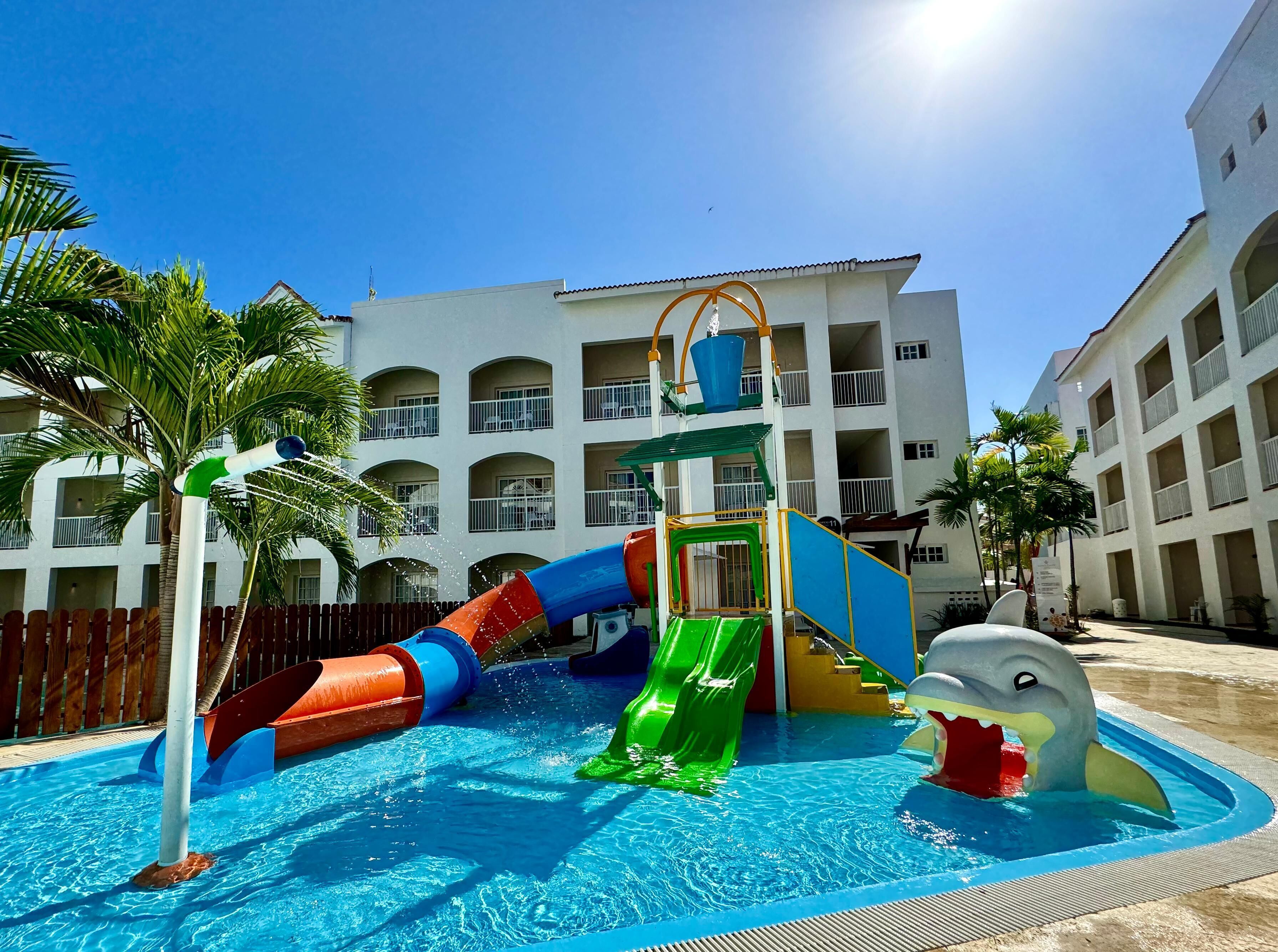 A swimming pool with a water slide and a shark-shaped play structure.