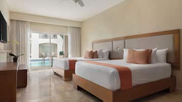 Habitación de hotel con dos camas, ventilador de techo, televisor y vista a una piscina.