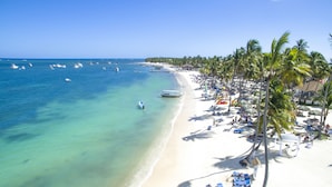 A beach with clear turquoise water, white sand, and palm trees.