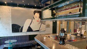 A bar area with a large mural, bar stools, a bar counter, and a seating area with a patterned couch. - Hotel Luzernerhof (Lucerne)