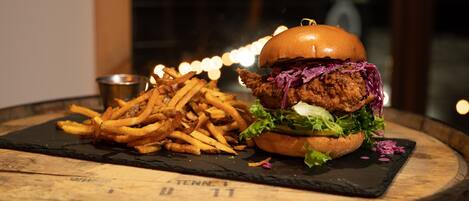 A burger and fries on a wooden table with a black slate.