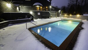 Una piscina rodeada de nieve, con un edificio al fondo.
