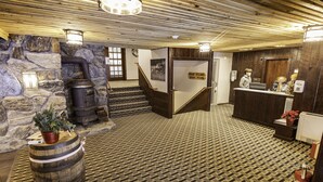 Un vestíbulo con pared de piedra, escalera de madera y una mesa de recepción.