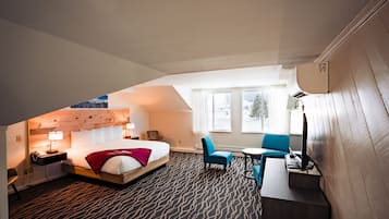 A hotel room with a bed, a desk, a chair, and a small table.