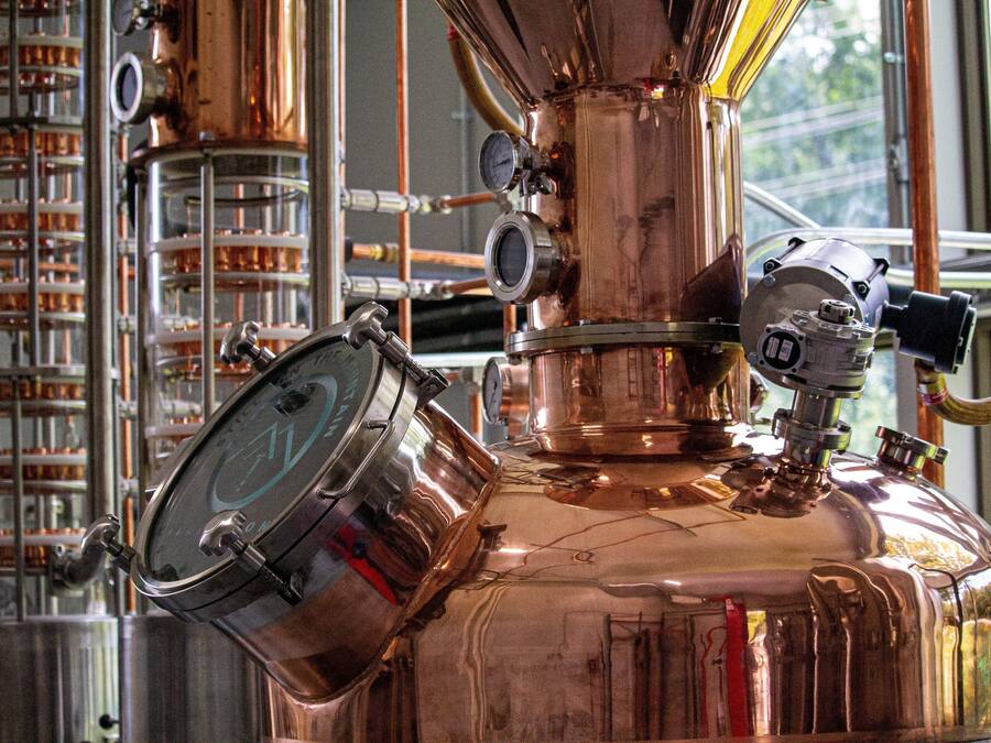 A copper distillation apparatus with gauges and valves, part of a distillation setup.