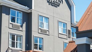 A building with a sign reading "Country Suites by Radisson." It features a modern design with a grey facade, multiple windows, and a brown roof. - Country Inn & Suites by Radisson, Myrtle Beach, SC (Myrtle Beach)