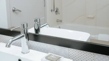 A bathroom with a white sink, a mirror, and a shower.