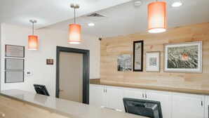 A hotel reception area with a wooden wall, framed pictures, and a reception desk with a computer. - Country Inn & Suites by Radisson, Myrtle Beach, SC (Myrtle Beach)