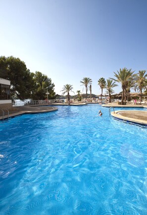 A large outdoor swimming pool with clear blue water, surrounded by palm trees and lounge chairs. - TRH Jardin Del Mar (Calvia)