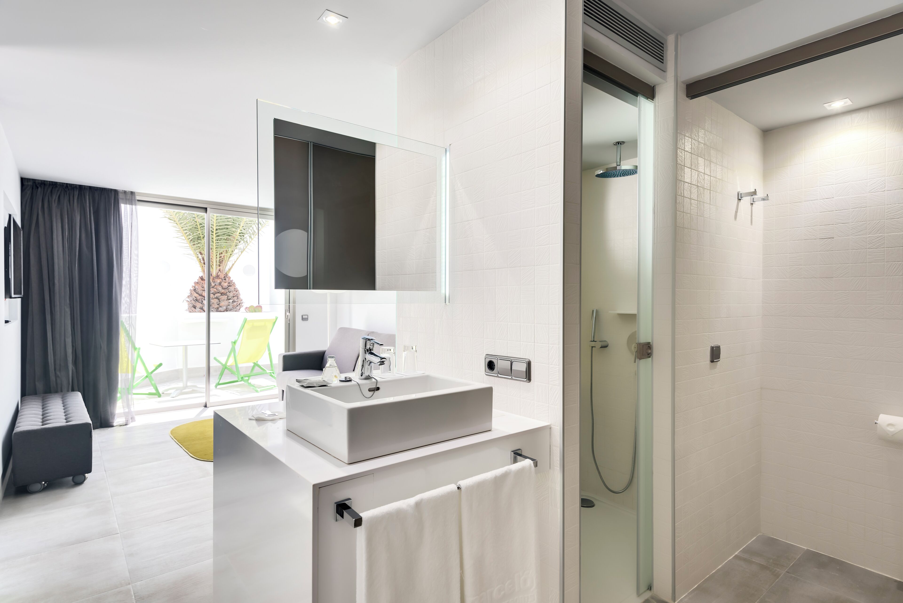 A modern bathroom with a large mirror, a rectangular sink, and a glass-enclosed shower.