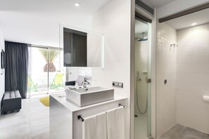 Un baño moderno con un espejo grande, un lavamanos rectangular y una ducha con mampara de cristal.