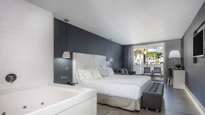 Una habitación de hotel moderna con una cama grande, una zona de estar separada, un escritorio pequeño y una bañera.