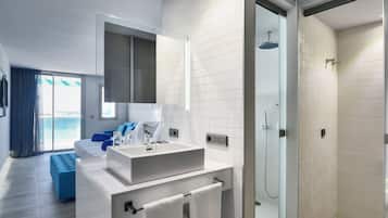 A modern bathroom with a glass shower enclosure, a white sink with a mirror, and a view of the sea through the glass door.