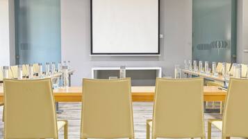 A conference room with a long table, multiple chairs, and a projector screen.