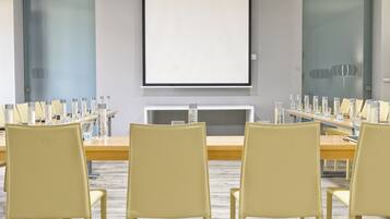A conference room with a long table, multiple chairs, and a projector screen.