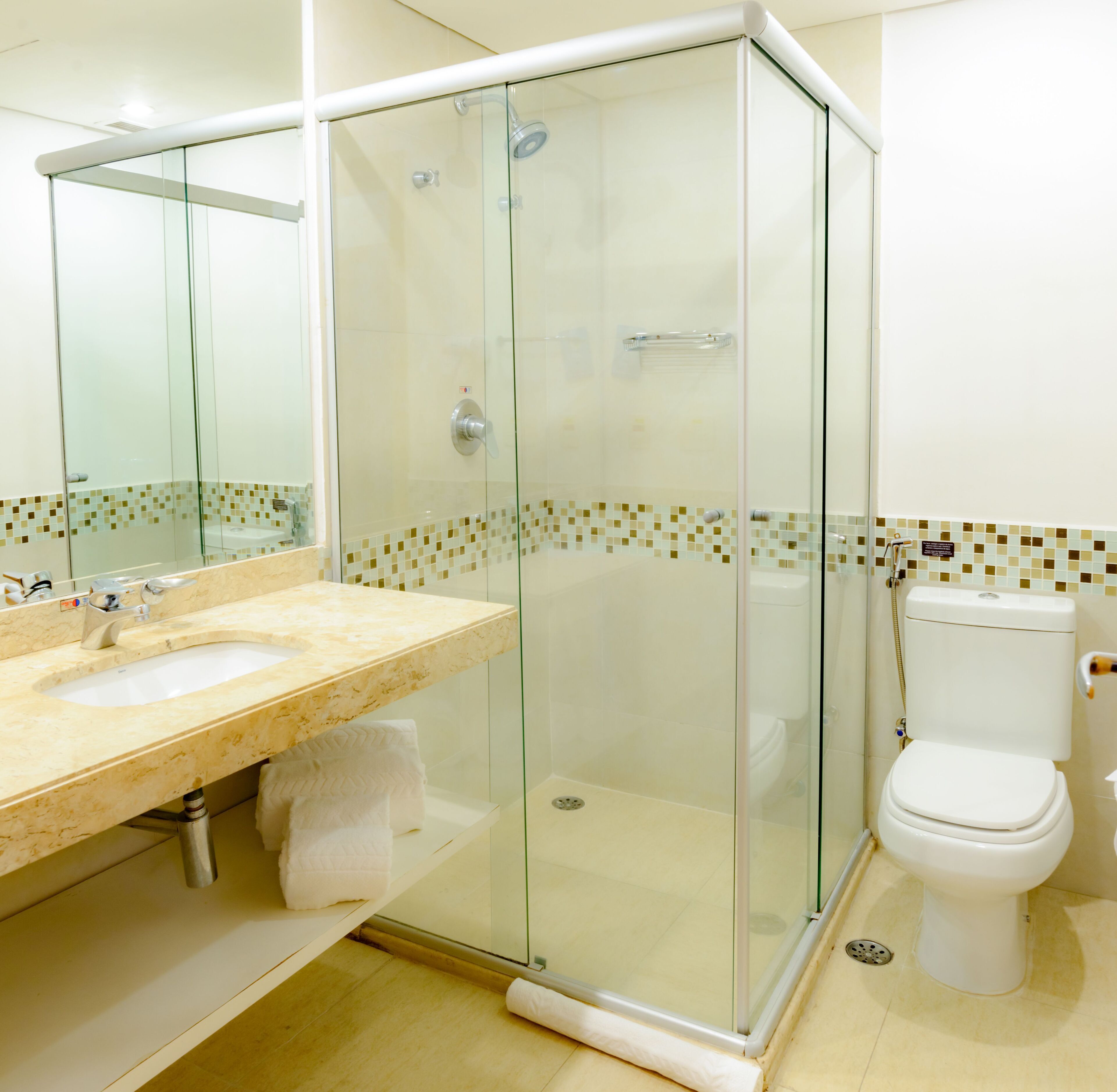 A modern bathroom with a glass-enclosed shower, a sink with a marble countertop, and a toilet.