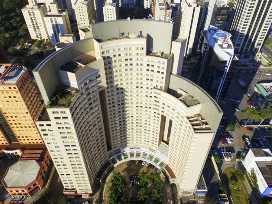 Un hotel moderno de gran altura con fachada curva, varios pisos y un patio central.