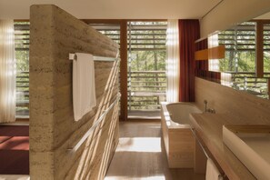 A modern bathroom with a large window, a wooden vanity, and a bathtub.