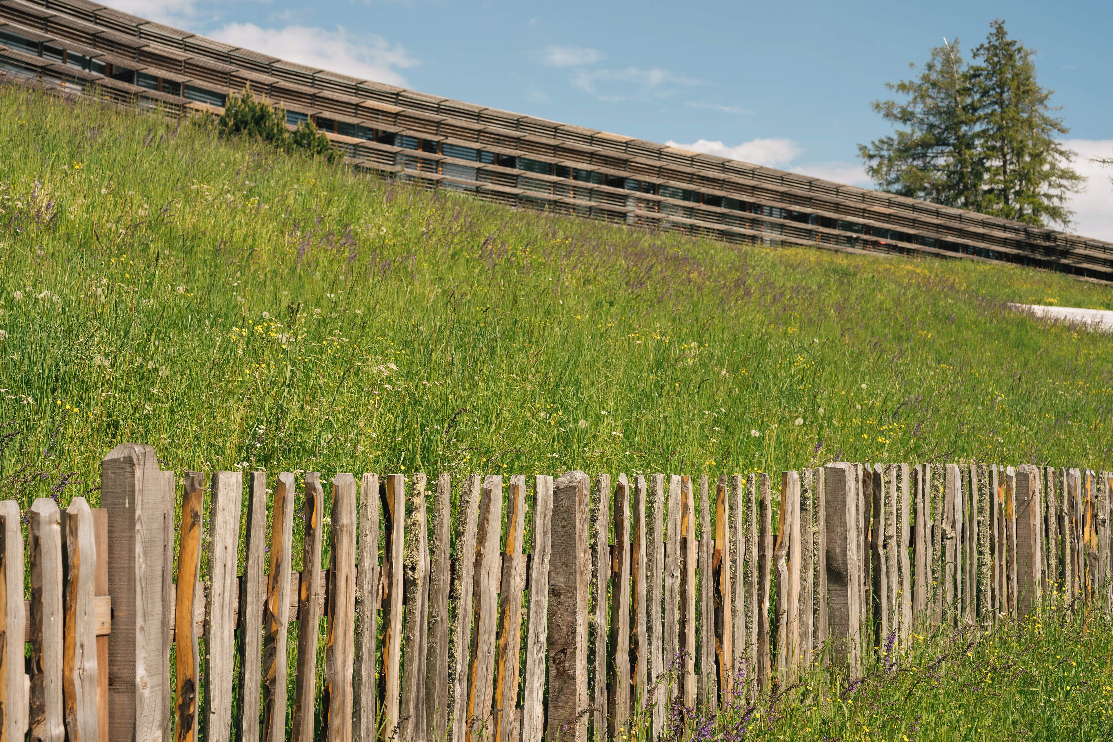 A wooden fence with a grassy field and a train in the background.