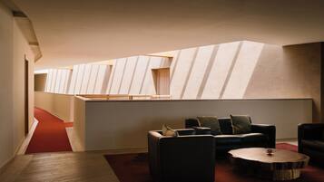 A modern interior with a sloped ceiling, a red carpeted hallway, and a seating area with a round coffee table.