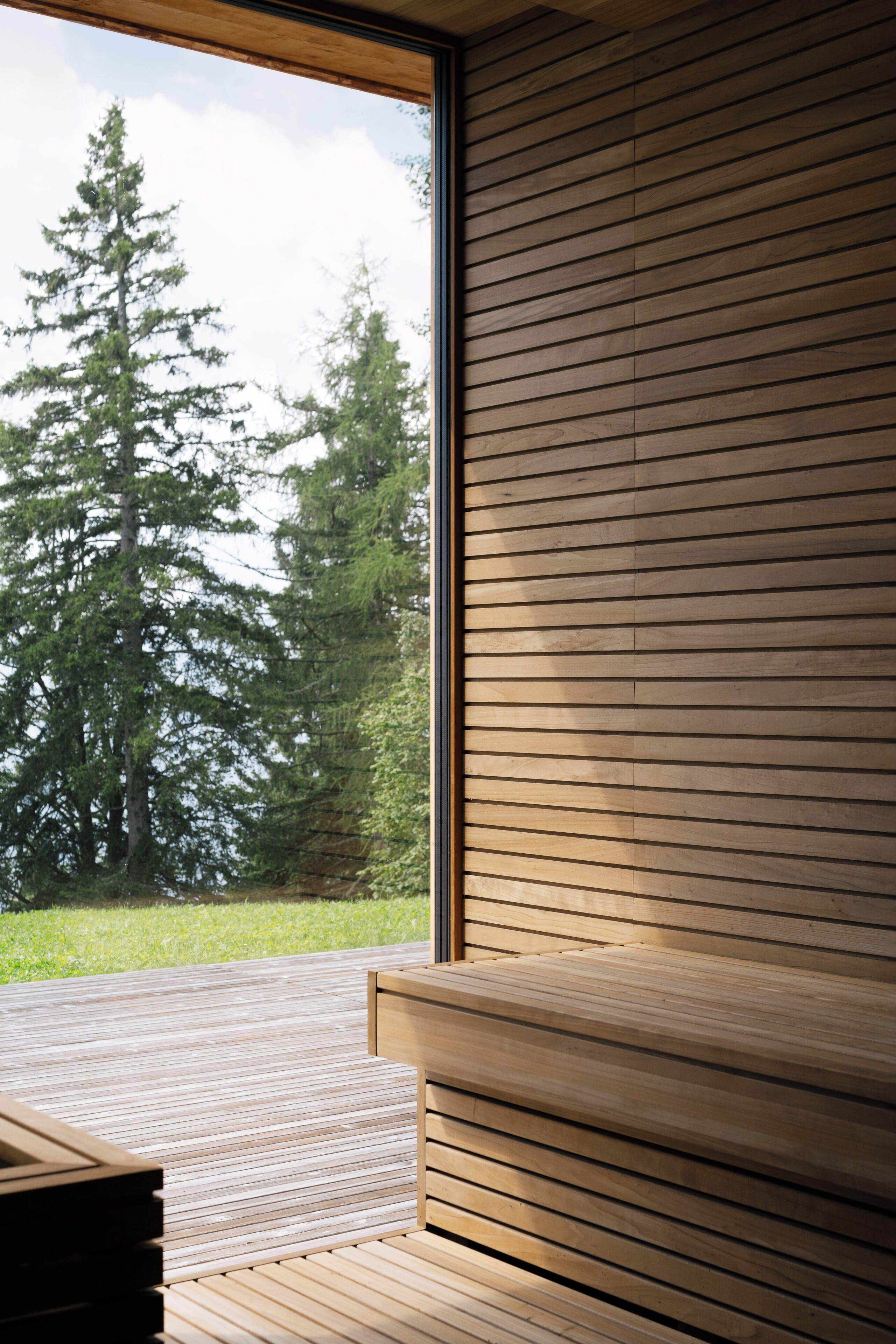 Un interior moderno con un banco de madera y un ventanal con vistas a un bosque.