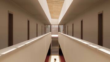 Un couloir avec une verrière, des poutres en bois et une moquette rouge.