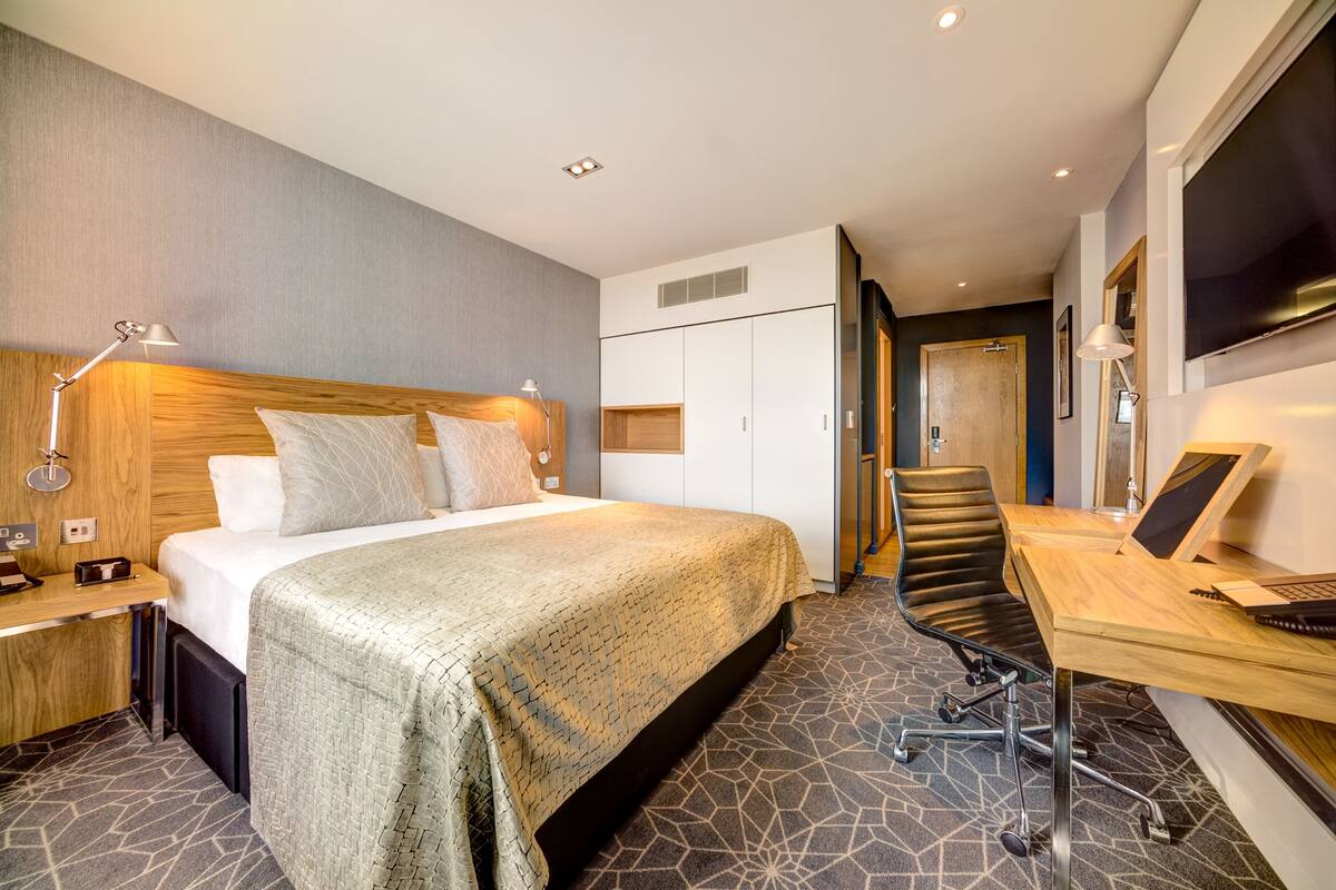 Een hotelkamer met een bed, bureau en stoel.