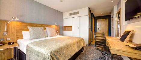 A hotel room with a bed, desk, and chair.