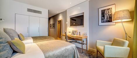 Une chambre d’hôtel avec un lit, un bureau, une chaise, une lampe et un tableau encadré au mur.
