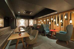 Un intérieur moderne avec des espaces aménagés pour s’asseoir, des tables et un mur décoratif orné de motifs géométriques.