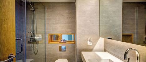 A modern bathroom with a glass shower enclosure, a white toilet, a large sink, and a mirror above the sink.