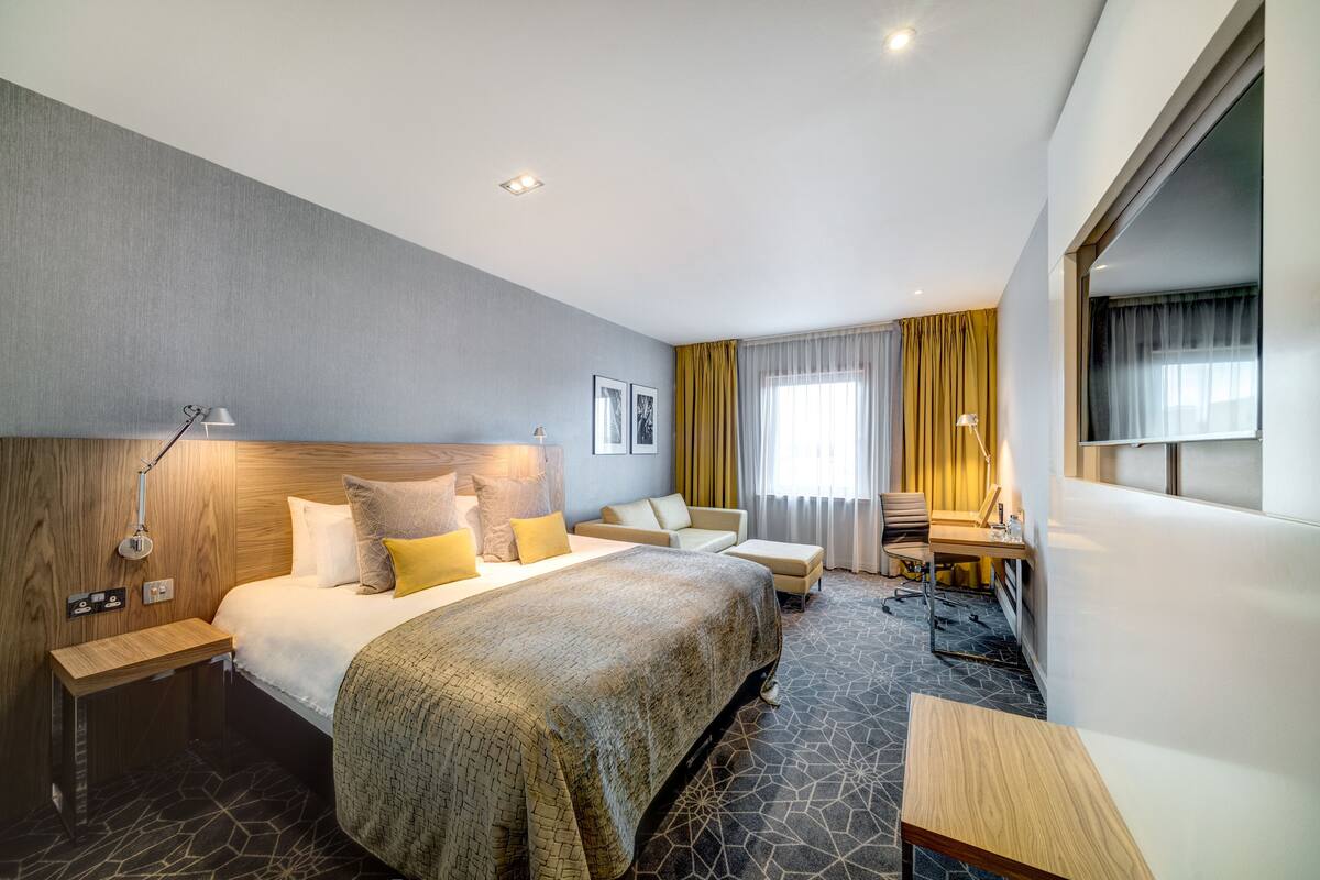 Een moderne hotelkamer met een groot bed, een bureau en een bank.