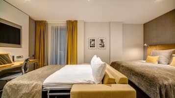 A hotel room with a bed, two bedside tables, a desk, a chair, a TV, and two framed pictures on the wall.