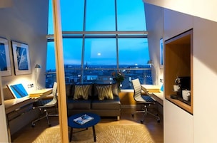 A modern office space with a large window, a sofa, a desk, and a coffee table.