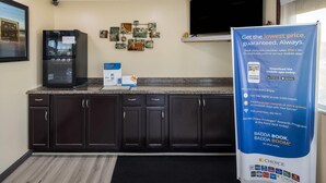A kitchen with dark cabinets, a granite countertop, a black refrigerator, and a wall-mounted security camera.