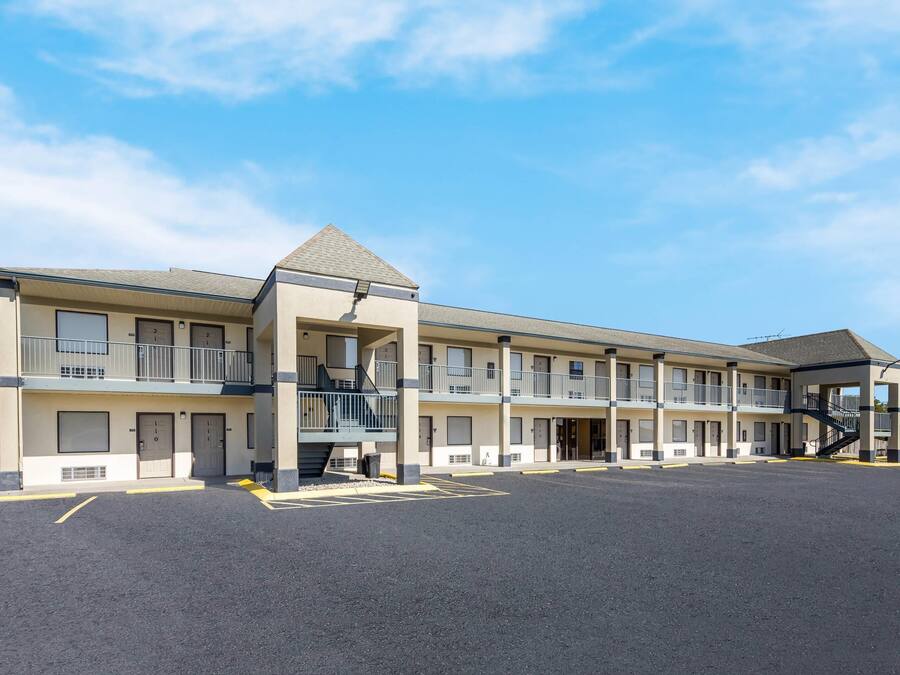 A multi-story motel with balconies, a parking lot, and a covered area.