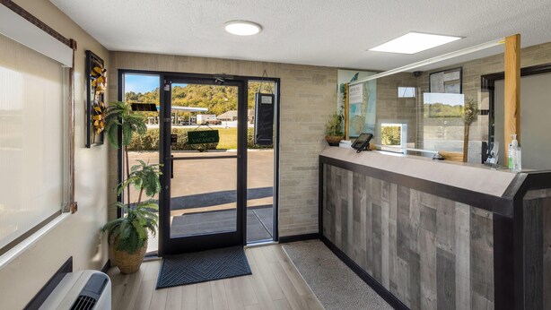 A reception area with a wooden reception desk, a large window, and a door leading outside.