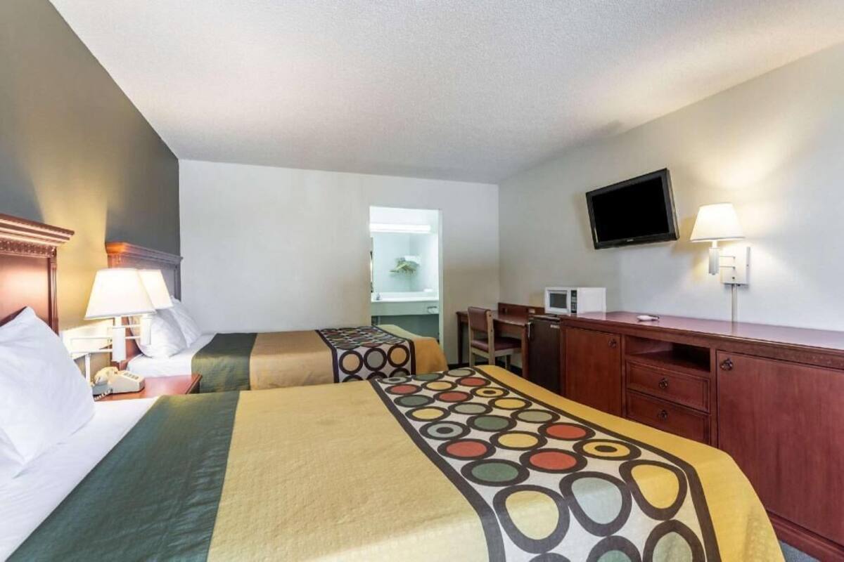 Una habitación de hotel con dos camas, un escritorio, un televisor y una ventana.