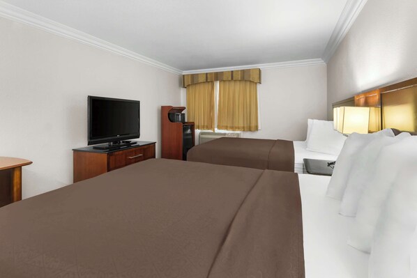 Habitación de hotel con dos camas, un televisor, un escritorio y una ventana con cortinas.