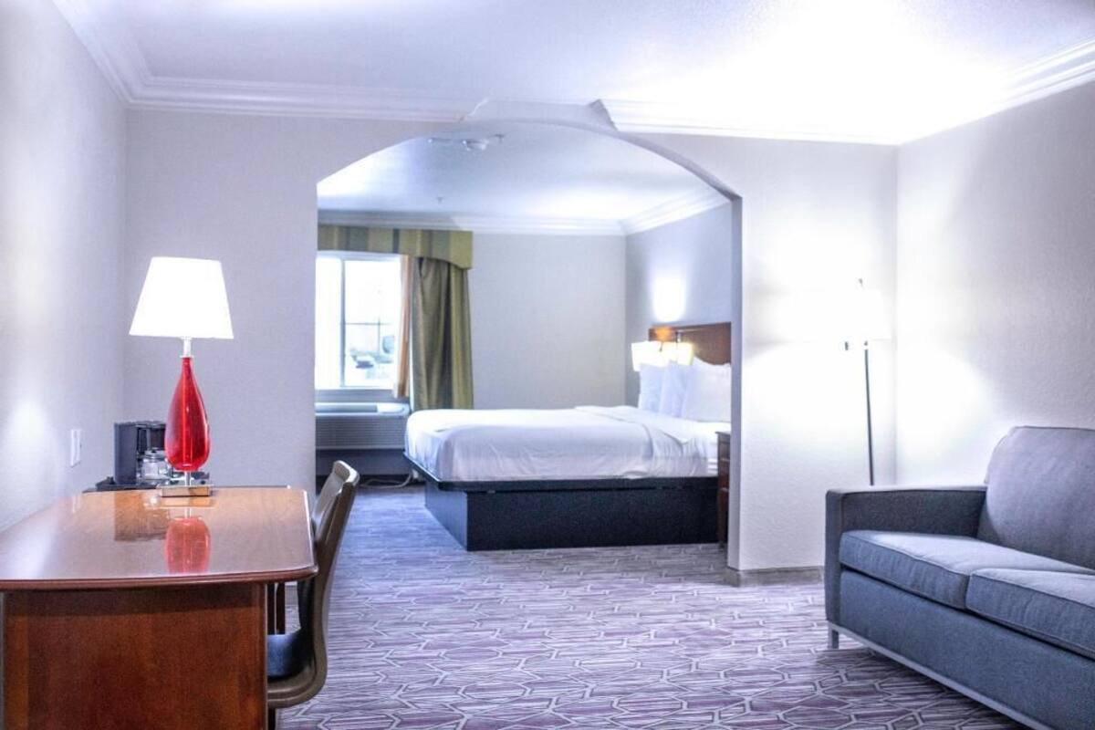 Une chambre d’hôtel avec un lit, un canapé, un bureau et une lampe.