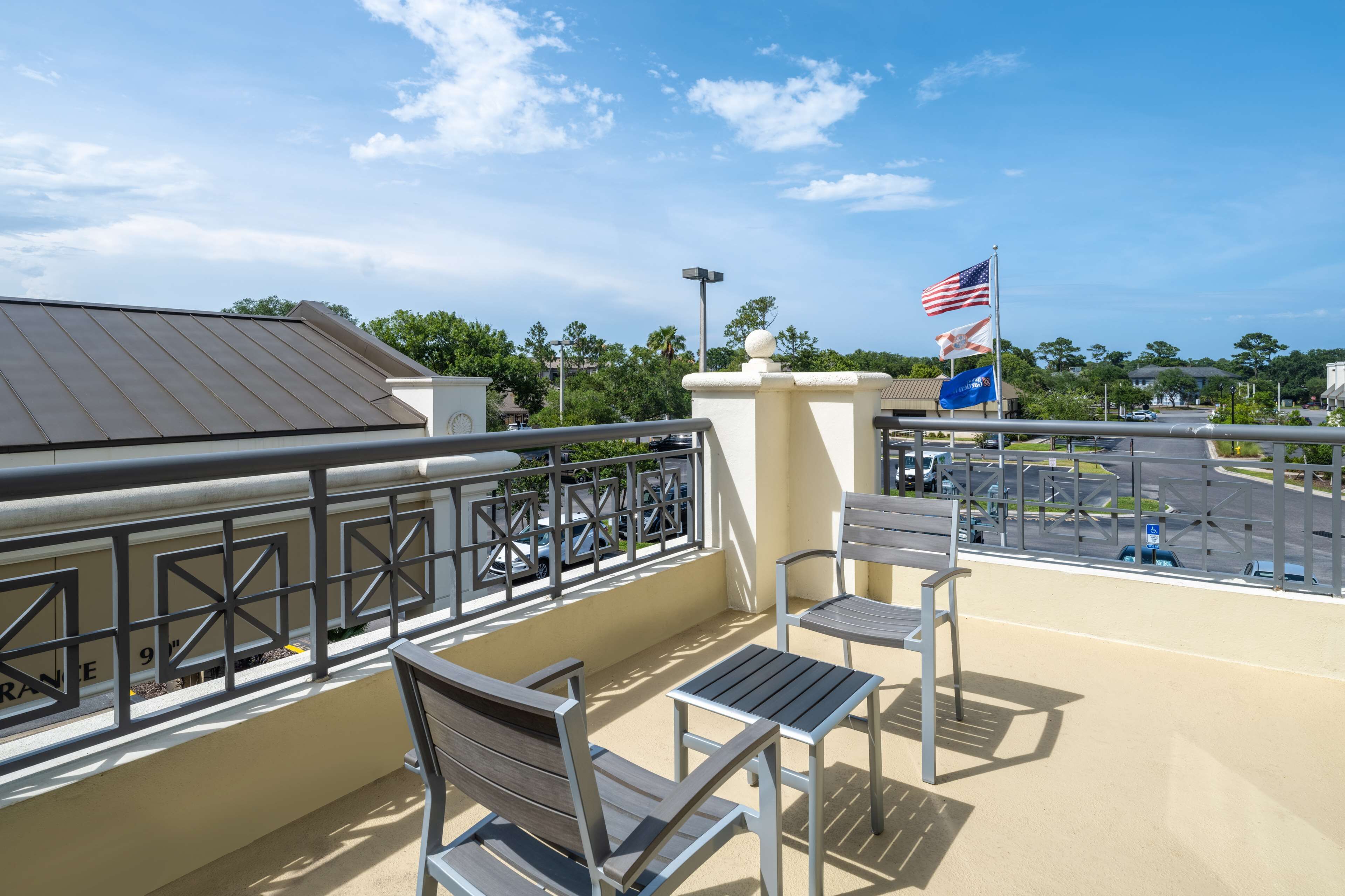 A balcony with metal railings, two wooden chairs, and a small table.