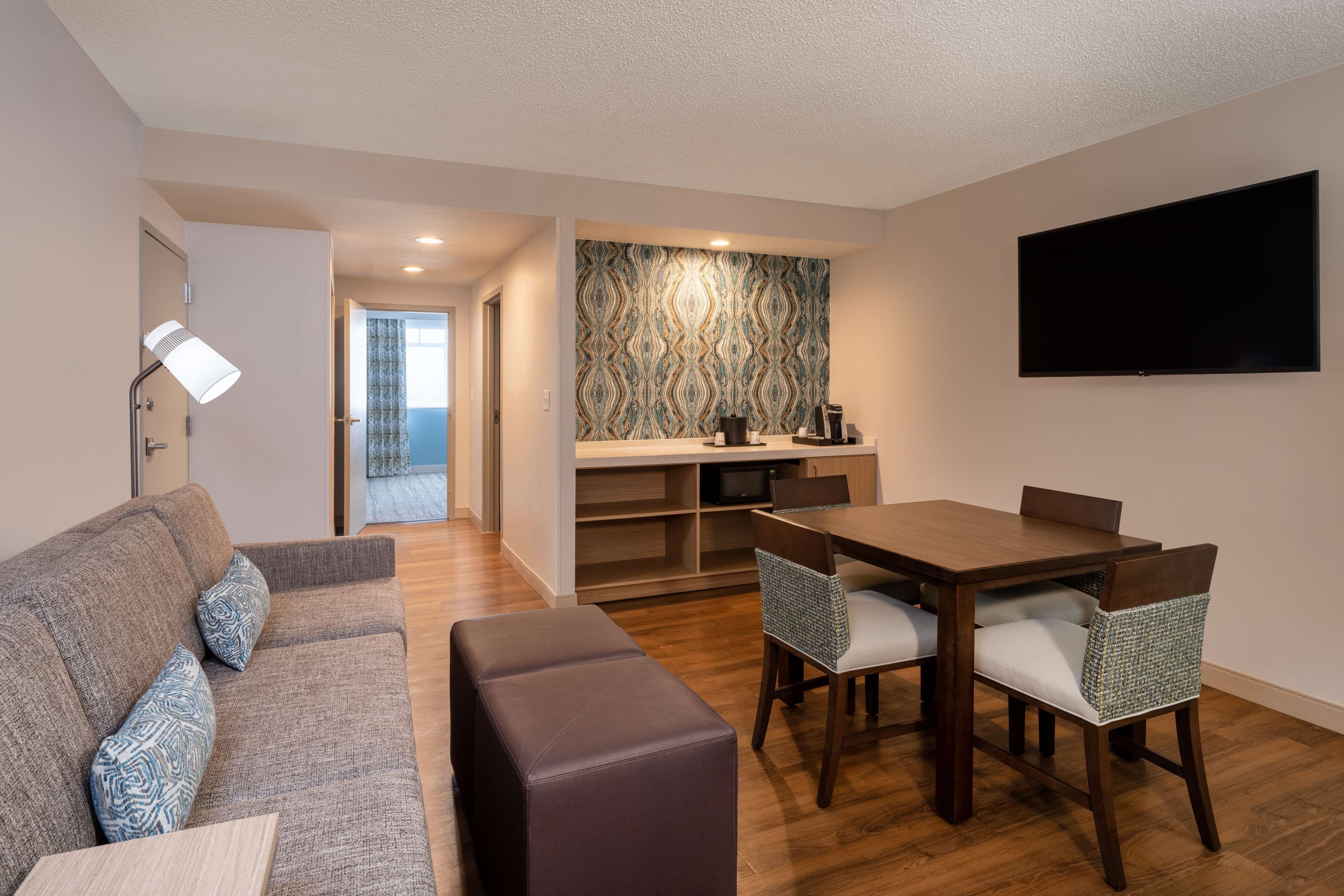 A modern living room with a sofa, a coffee table, and a dining area with a table and chairs.