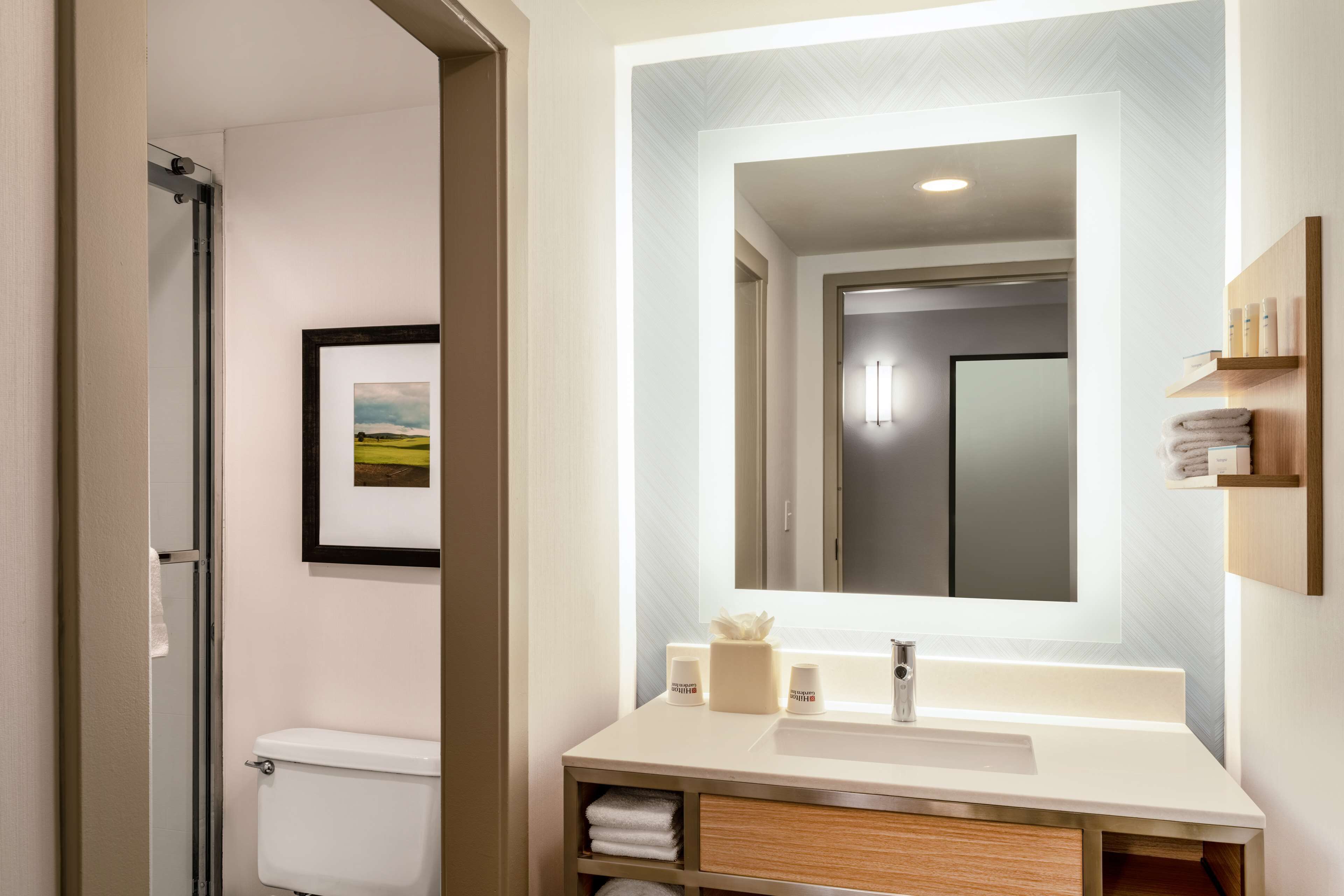 Un baño moderno con inodoro, lavabo y espejo.