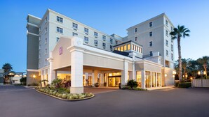 A multi-story hotel with a central entrance, large windows, and a well-lit facade. - Hilton Garden Inn Jacksonville Ponte Vedra Sawgrass (Ponte Vedra Beach)
