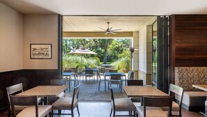 An indoor dining area with tables and chairs, a ceiling fan, and a view of the outdoors. - Hilton Garden Inn Jacksonville Ponte Vedra Sawgrass (Ponte Vedra Beach)