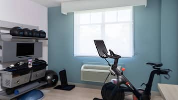 A room with a stationary bike, a TV, and exercise equipment.